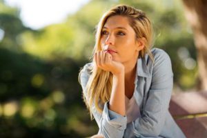 thoughtful woman sitting alone outdoors